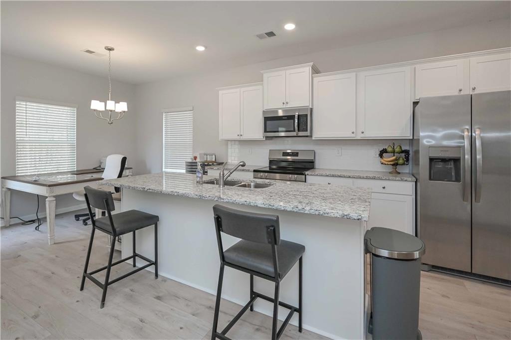 505 Charleston Place Villa Rica, GA 30180 - Photo 14 of 35 a kitchen with stainless steel appliances granite countertop a table chairs refrigerator and a sink