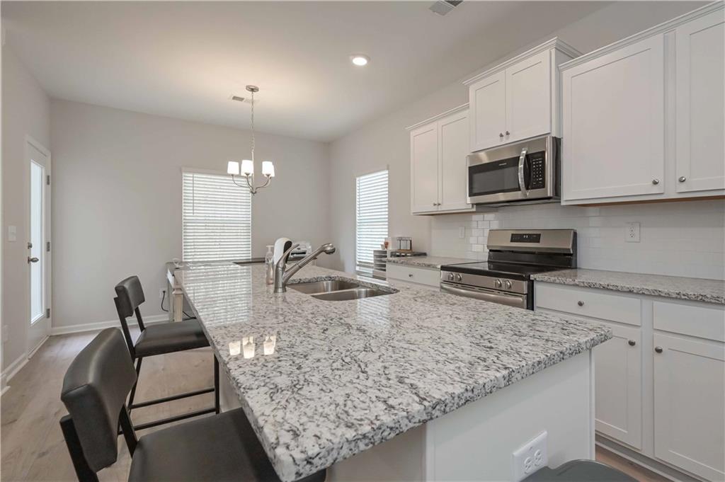 505 Charleston Place Villa Rica, GA 30180 - Photo 16 of 35 a kitchen with stainless steel appliances granite countertop a sink a stove and a white cabinets