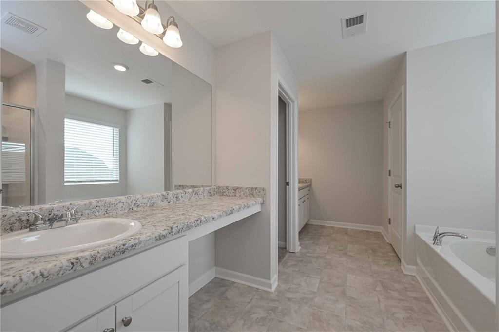 505 Charleston Place Villa Rica, GA 30180 - Photo 30 of 35 a bathroom with a granite countertop sink a toilet and bathtub