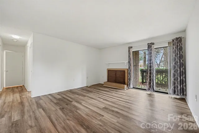 a view of an empty room with wooden floor and a fireplace