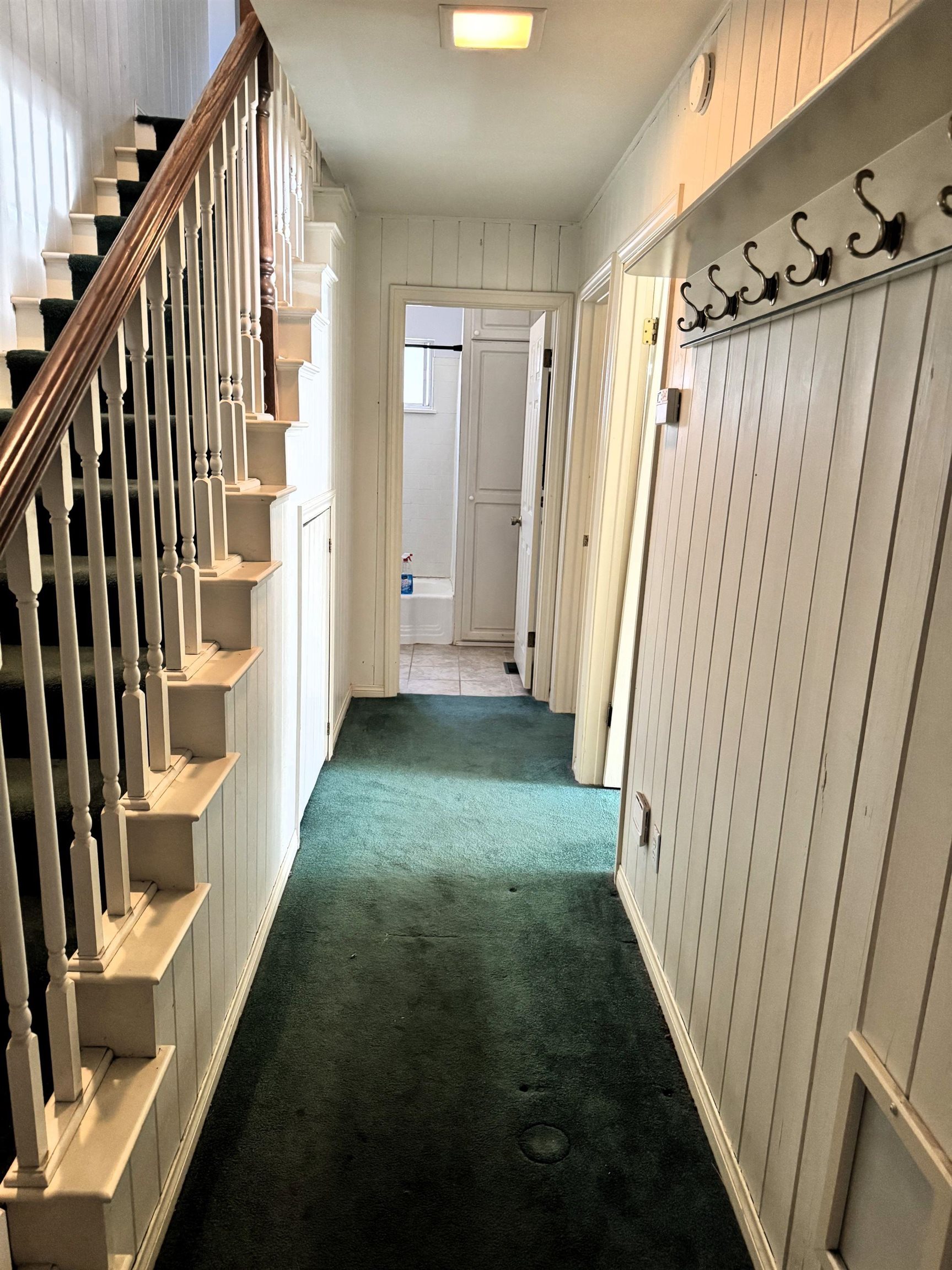 4 Kelley Road, Unit 1 Mammoth Lakes, CA 93546 - Photo 13 of 19 Hallway featuring vertical plank wall paneling, a wooden staircase with white balusters, and green carpet flooring