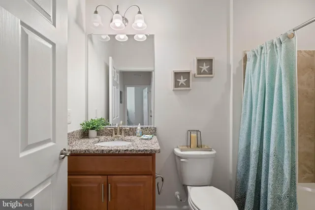 a bathroom with a granite countertop sink a toilet and a mirror