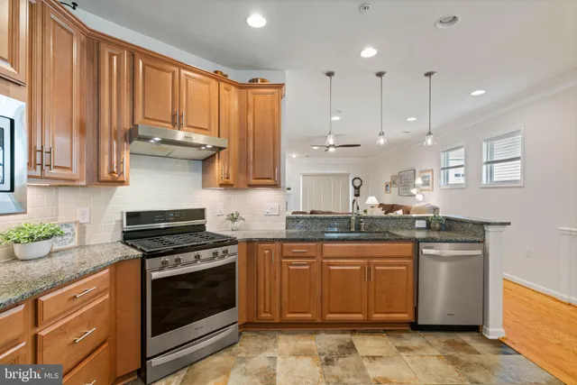 a kitchen with stainless steel appliances granite countertop a stove a sink and a microwave