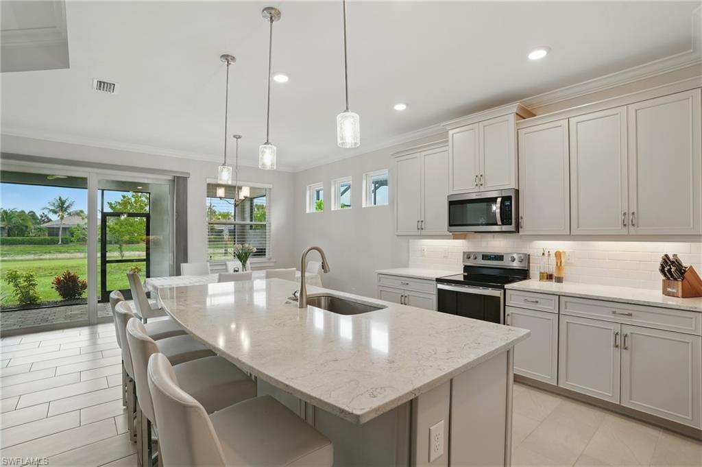 28165 Captiva Shell Loop Bonita Springs, FL 34135 - Photo 10 of 38 a kitchen with stainless steel appliances granite countertop a sink a stove and a wooden floors