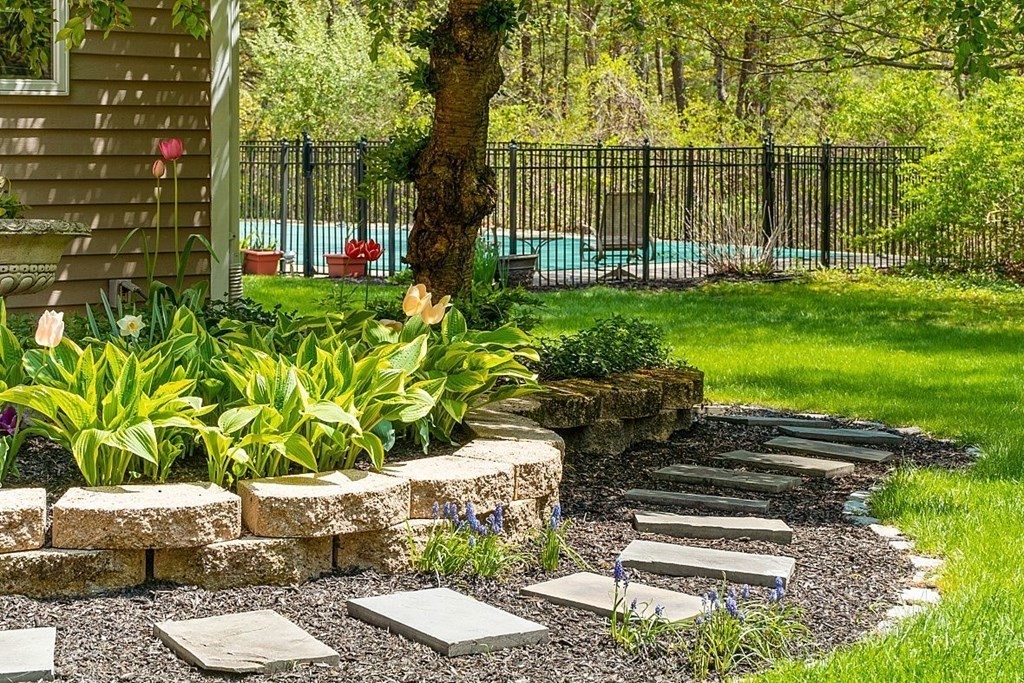 793 Reservoir Road Lunenburg, MA 01462 - Photo 5 of 39 a garden with a bench in front of the house