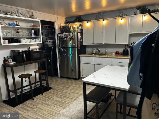 a kitchen with stainless steel appliances granite countertop a refrigerator a stove and white cabinets with wooden floors