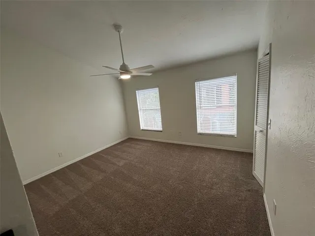 an empty room with windows and fan