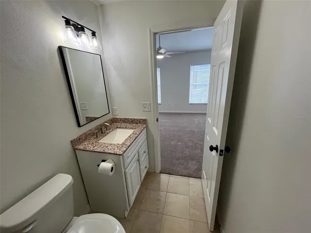 a bathroom with a granite countertop sink mirror vanity and toilet