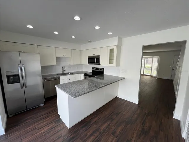 a large kitchen with stainless steel appliances granite countertop a stove a sink a refrigerator and a microwave