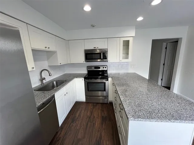 a kitchen with granite countertop a sink and steel appliances