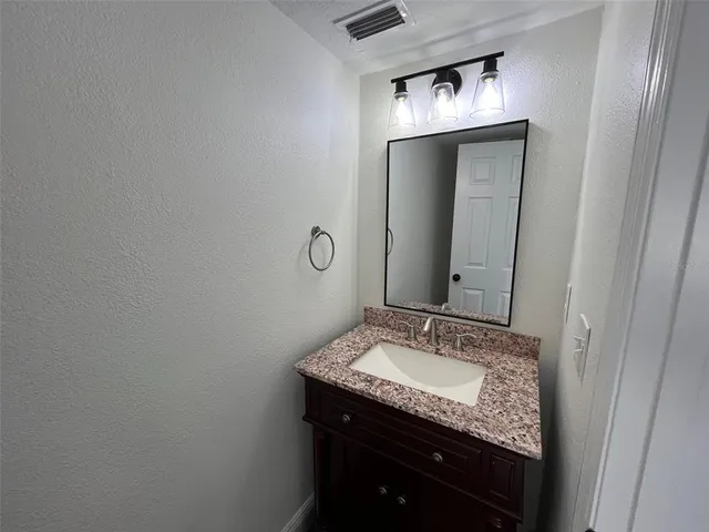 a bathroom with a granite countertop sink and a mirror