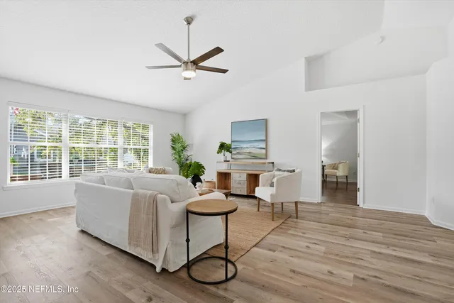 a living room with couches a coffee table and a large window with wooden floor