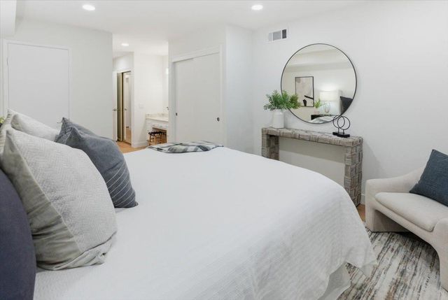 a bedroom with a bed mirror and lamp