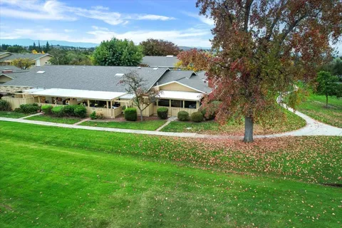 a view of house with a big yard and large trees