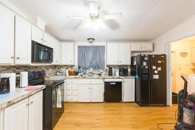 a kitchen with a refrigerator a stove top oven a sink dishwasher and white cabinets with wooden floor