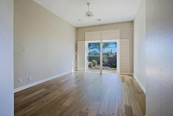 a view of an empty room with a window and wooden floor