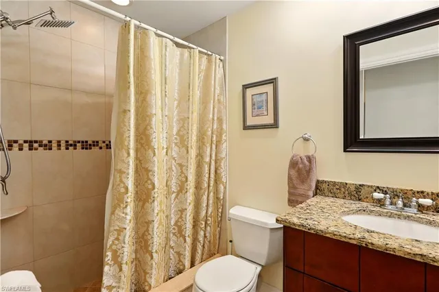a bathroom with a granite countertop sink toilet and shower