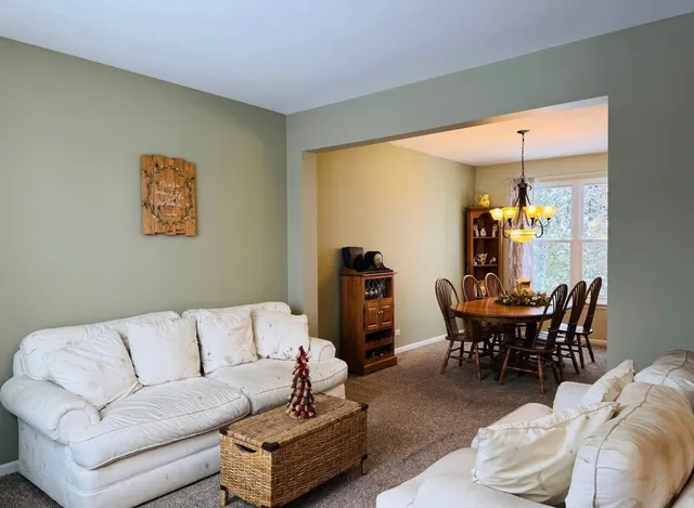 a living room with furniture a chandelier and a dining table