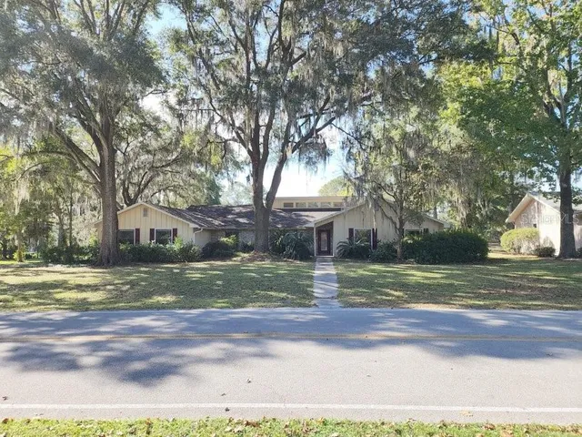 a view of a yard in front of a house with large trees