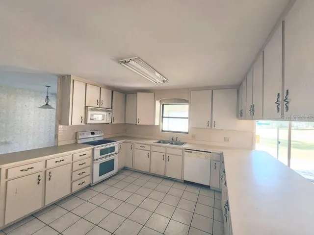 a large white kitchen with a sink and cabinets