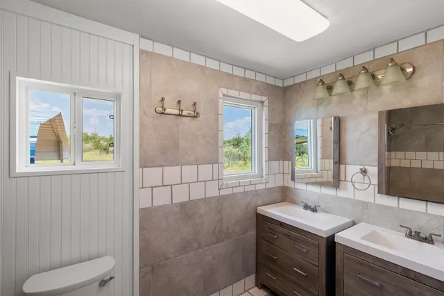 a bathroom with a double vanity sink toilet and a mirror
