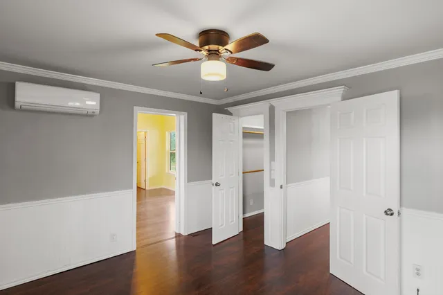 an empty room with wooden floor chandelier fan and windows