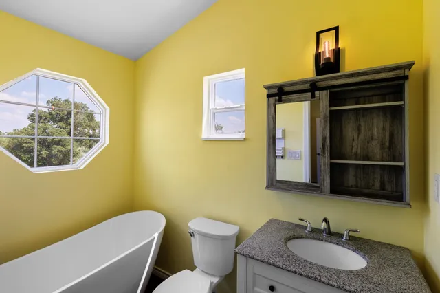 a bathroom with a granite countertop sink a mirror and a toilet