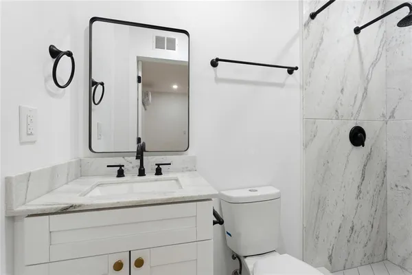 a bathroom with a granite countertop sink toilet and shower