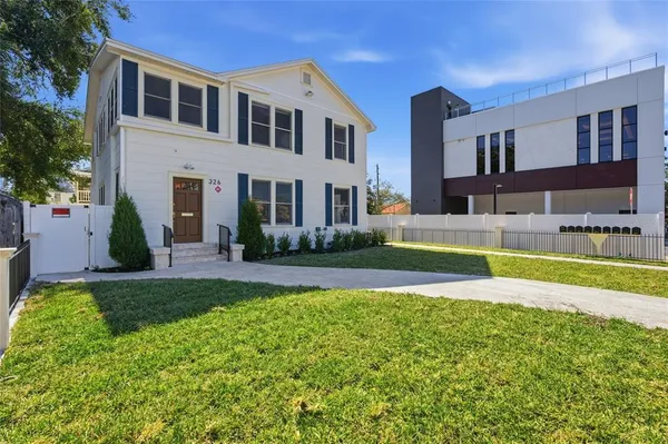 a view of house with a big yard and potted plants
