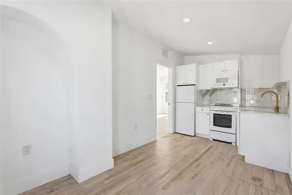 a kitchen with wooden floors white cabinets and stainless steel appliances