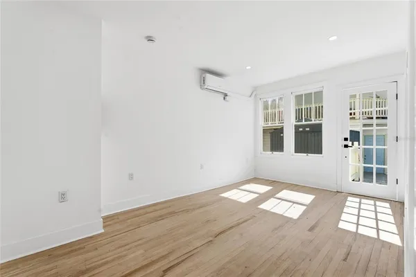 an empty room with wooden floor and windows