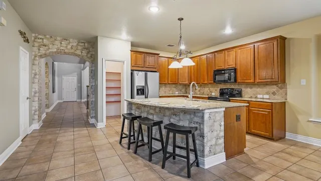 a kitchen with stainless steel appliances granite countertop a stove top oven a sink a refrigerator and a granite counter tops