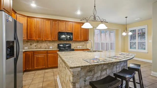 a kitchen with a stove a sink a refrigerator a dining table and chairs