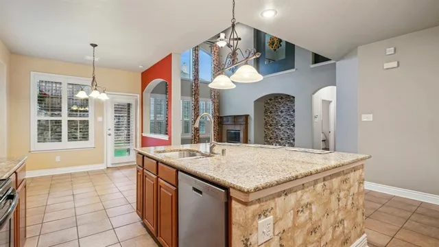a view of kitchen island with granite countertop a sink a stove top oven a clock and a window