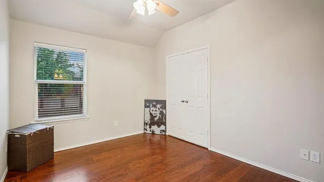 a view of an empty room with wooden floor and a bathroom