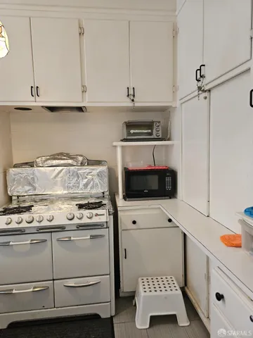 a kitchen with a stove and white cabinets