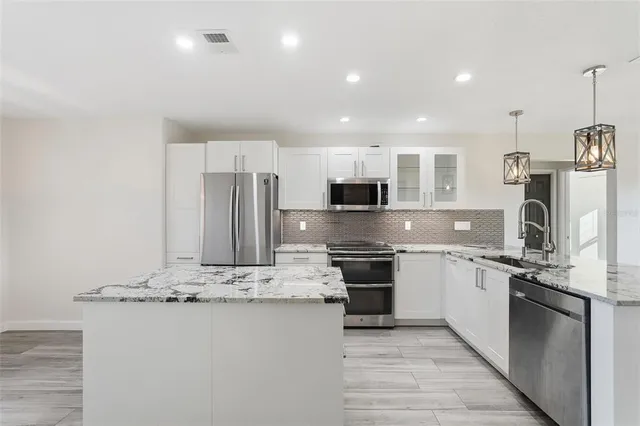 a large kitchen with stainless steel appliances kitchen island granite countertop a stove and a sink