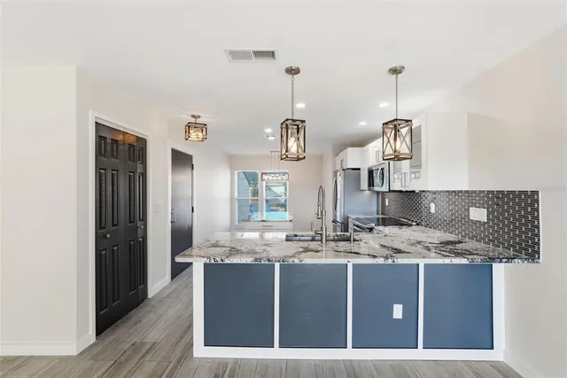 a kitchen with kitchen island granite countertop a sink a counter top space and cabinets