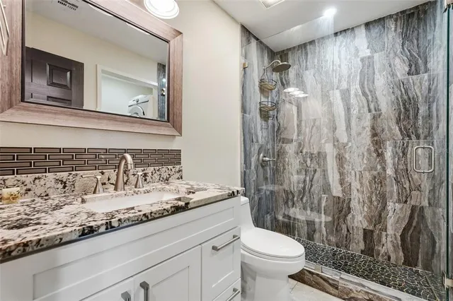 a bathroom with a granite countertop sink toilet and shower