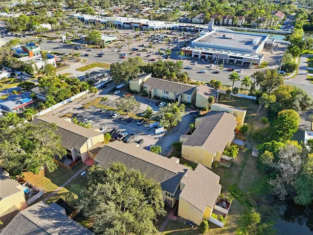 an aerial view of a residential apartment building with a yard and parking spaces