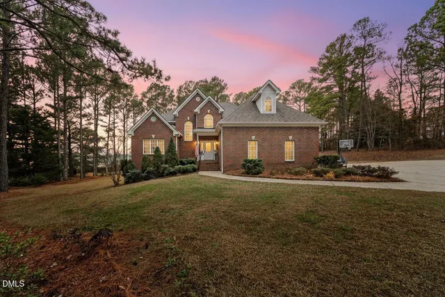 a front view of a house with a garden and trees