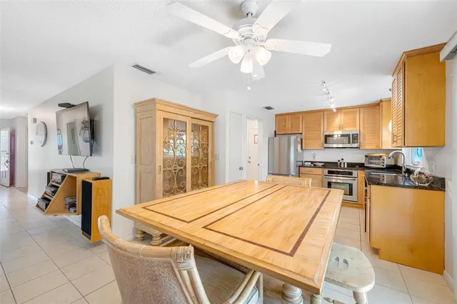a kitchen with stainless steel appliances kitchen island granite countertop a refrigerator a stove a sink a dining table and chairs with wooden floor