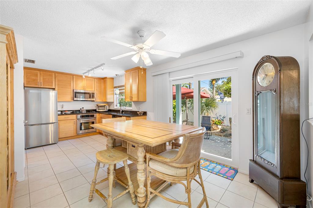 119 13th Avenue Indian Rocks Beach, FL 33785 - Photo 14 of 32 a kitchen with stainless steel appliances kitchen island granite countertop a refrigerator a stove a sink a dining table and chairs with wooden floor