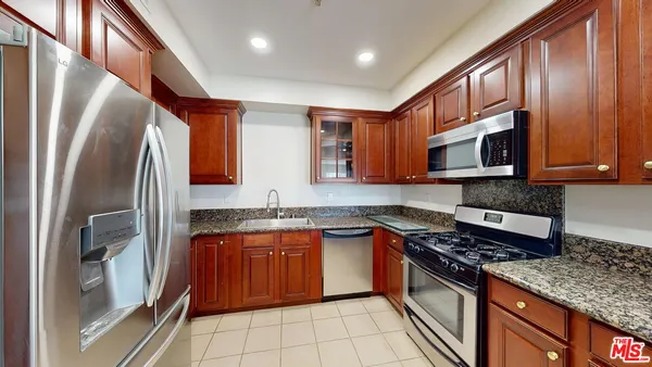 a kitchen with stainless steel appliances granite countertop a stove top oven a sink dishwasher a refrigerator and a microwave