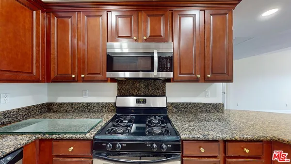 a kitchen with granite countertop a stove and cabinets