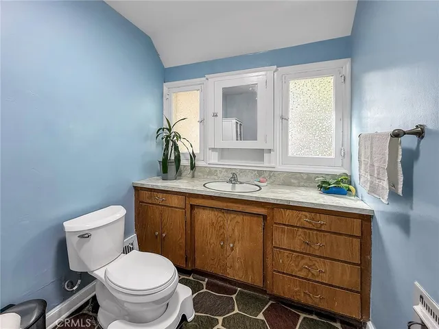 a bathroom with a toilet a sink a mirror a window and vanity
