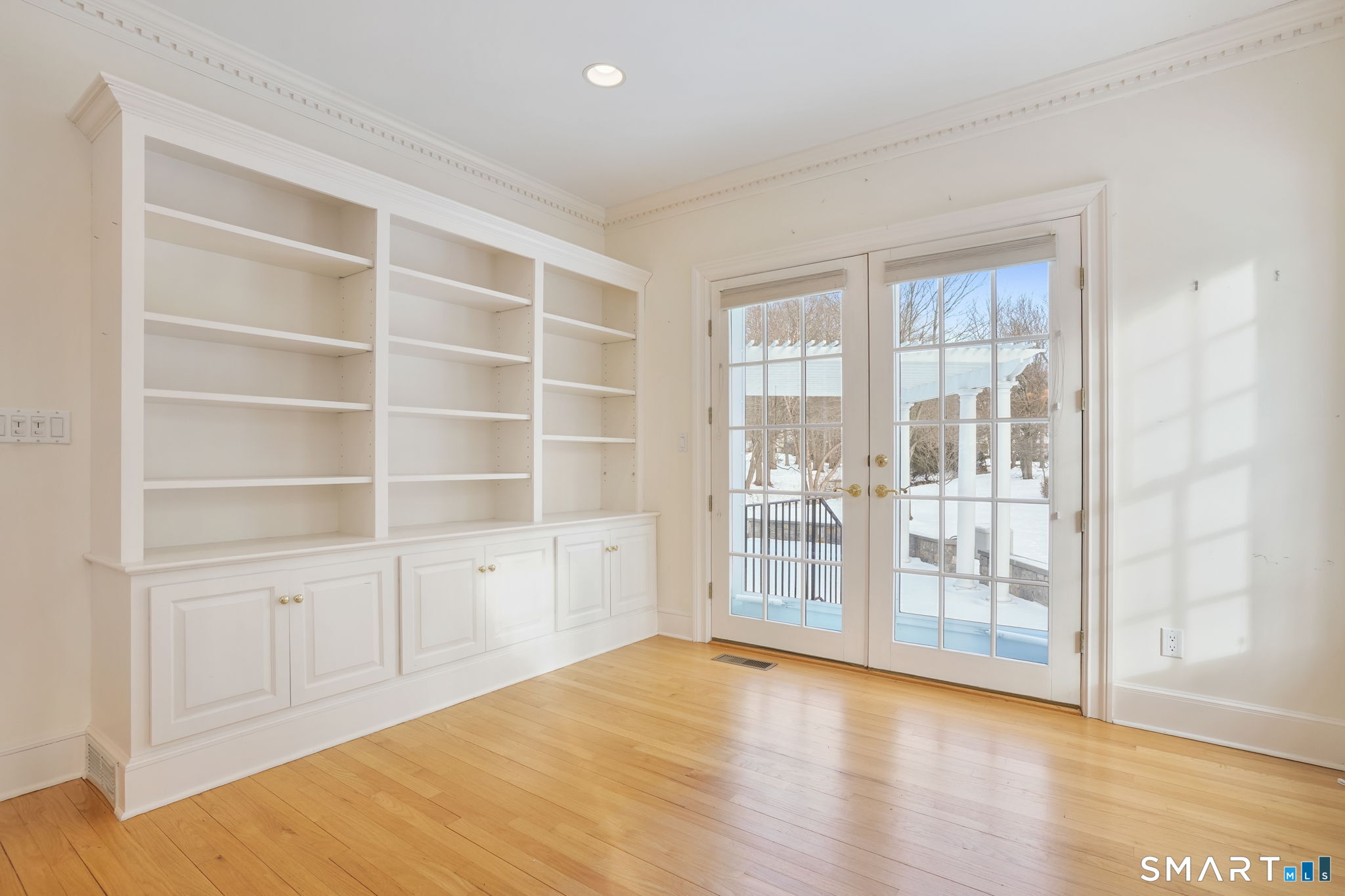 a view of an empty room with wooden floor and a window
