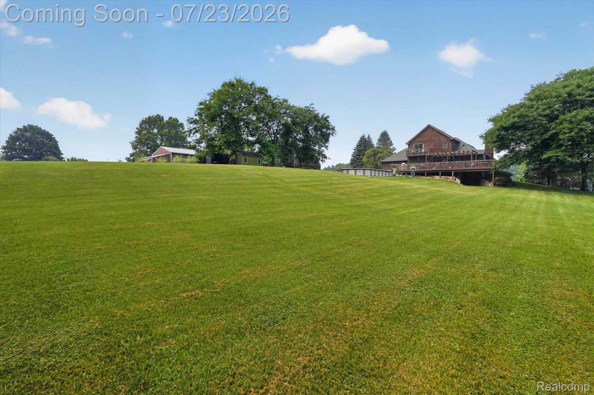2795 Bird Road Ortonville, MI 48462 - Photo 50 of 62 Expansive green lawn with a distant two-story residence featuring a multi-level wood deck and an above-ground pool