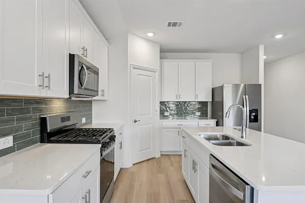 a kitchen with stainless steel appliances white cabinets and wooden floor