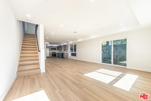 a view of an empty room with wooden floor and stairs